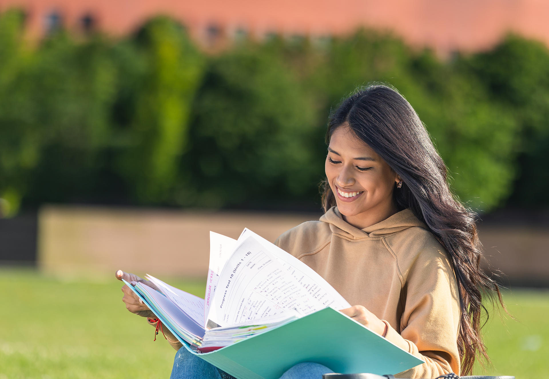 Happy young woman studying outside at college campus.