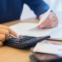 A man's hand holding pen and using calculator