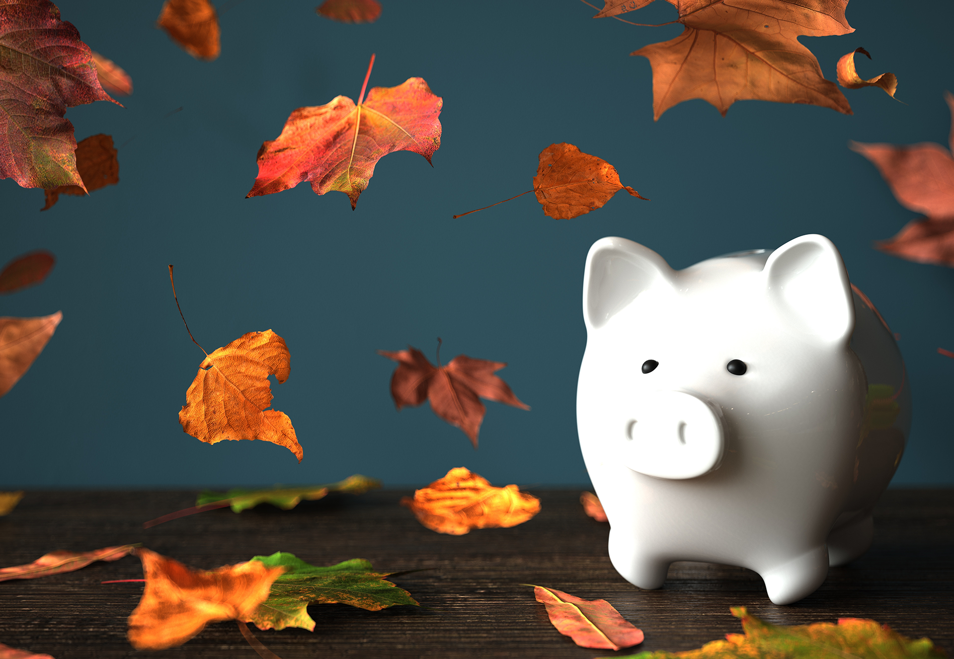 White piggy bank with fall leaves around it